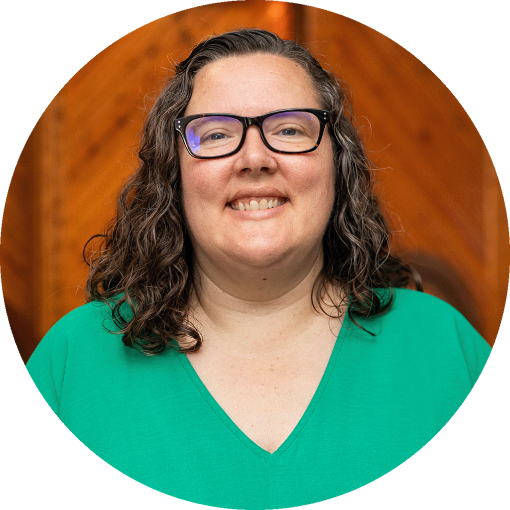 lady with curly brown hair and glasses.