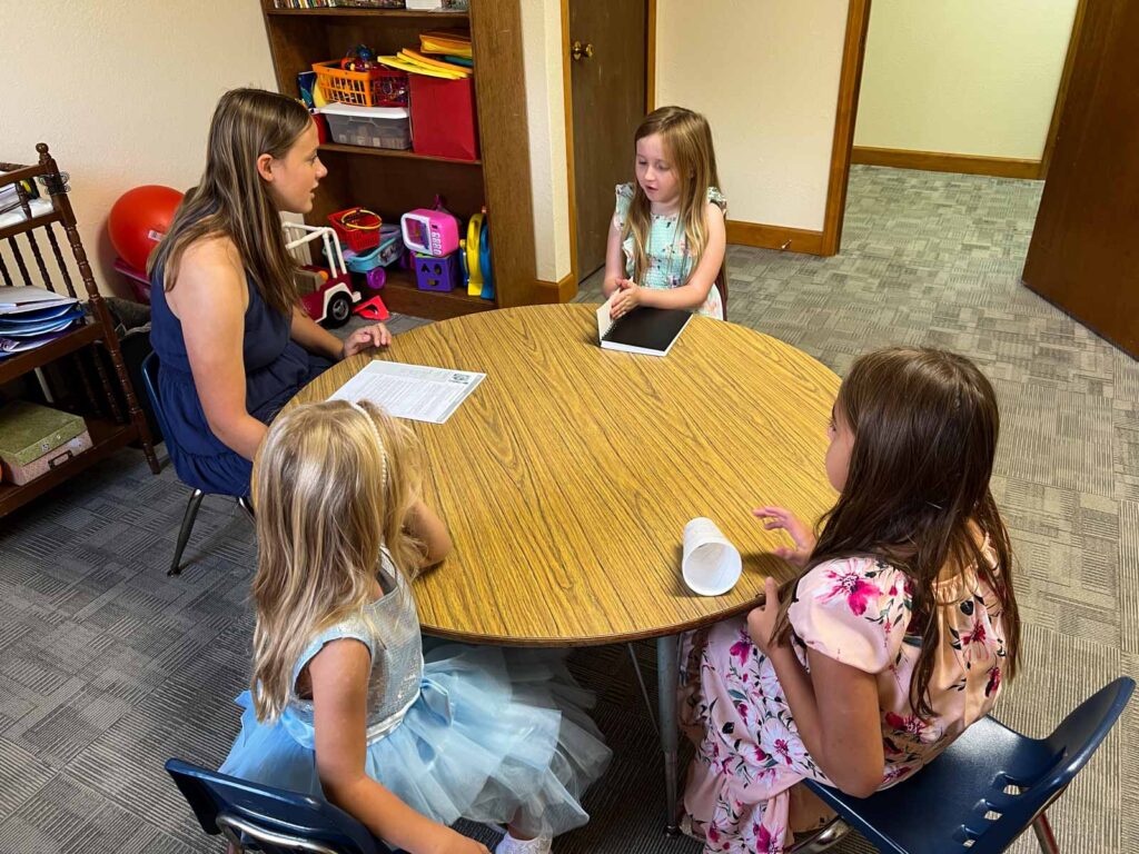 teenage girl and three smaller girls sitting at a round table.