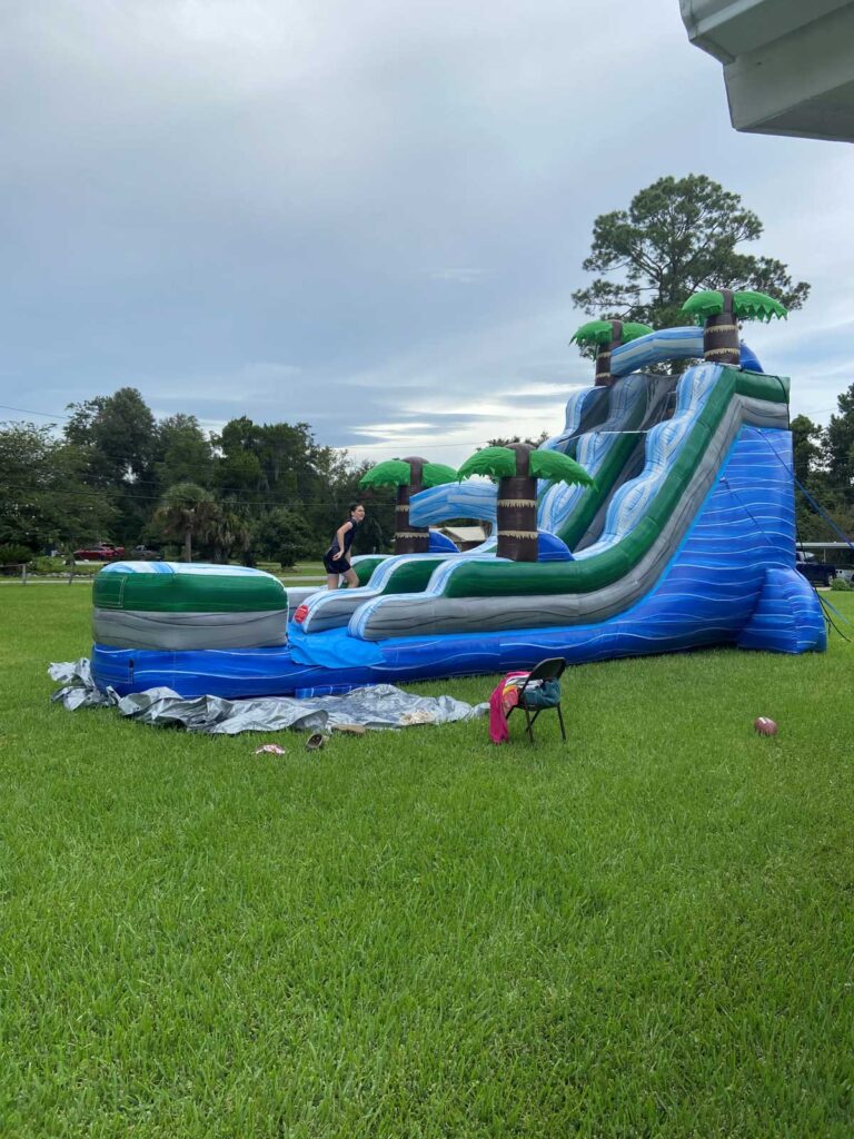 a teenage girl playing on a large inflatable water slide.