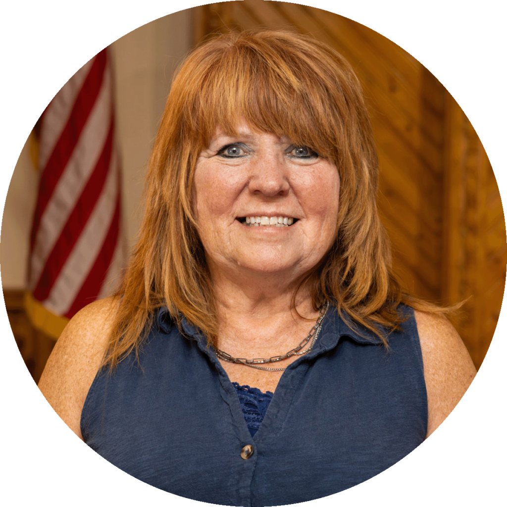 smiling woman with auburn hair and a navy blouse.
